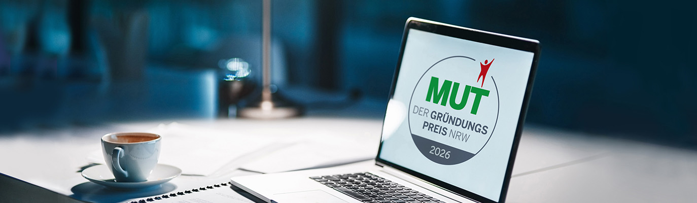 Laptop auf einem Schreibtisch, auf dem Bildschirm ist das Logo von „MUT – Der Gründungspreis NRW 2026“ zu sehen.